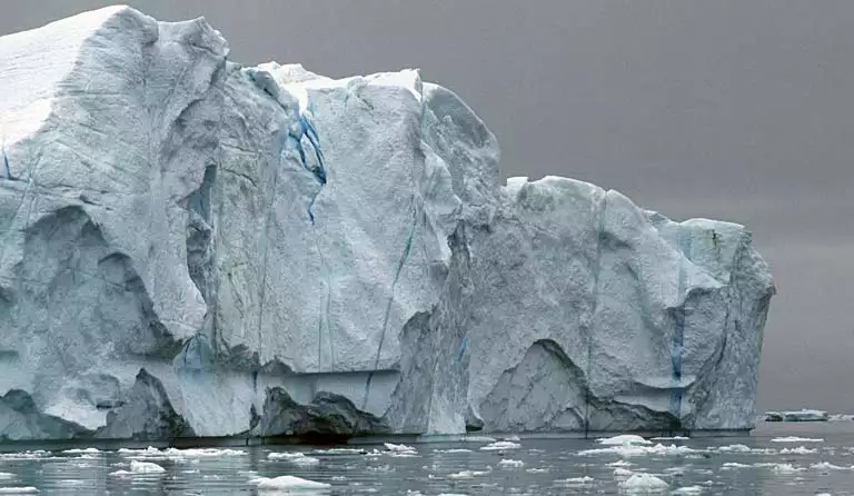 K&aelig;mpe isfjeld med spr&aelig;kker bev&aelig;ger sig langsomt ud mod mundingen af isfjorden.